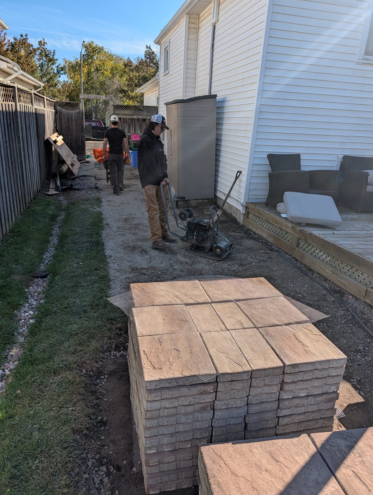 Pallet of pavers staged next to a compacted base while the crew works